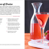 Page out of a book. Strawberry-themed cocktail with a glass and carafe on a table, accompanied by strawberries.