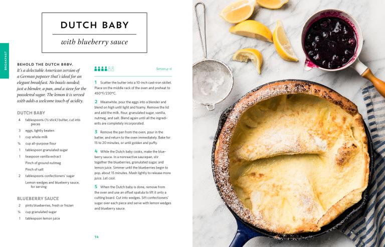 Dutch baby with blueberry sauce on a marble surface with a recipe card.