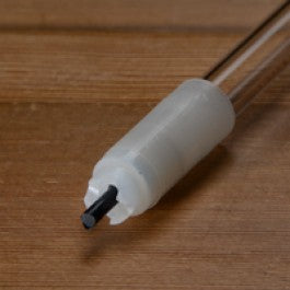Plastic tube with a spring loaded tip on a wooden surface with a black background