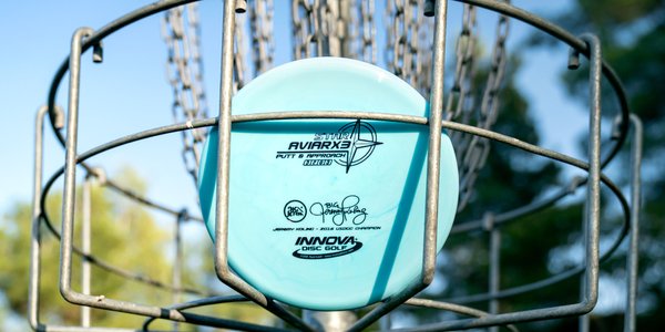 Disc golf disc with branding on a disc golf basket