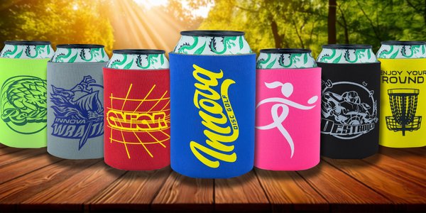 Assorted colorful can coolers with various designs on a wooden surface.