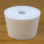 White rubber bottle stopper with hole on a wooden background
