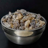 Metal bowl filled with raw sugar chunks on a black background