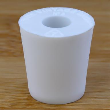White rubber bottle stopper with hole on a wooden background