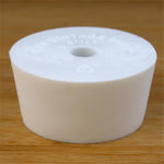 White rubber bottle stopper with hole on a wooden background