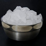 Metal bowl filled with white sugar chunks on a black background