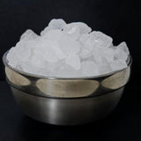 Metal bowl filled with white sugar chunks on a black background