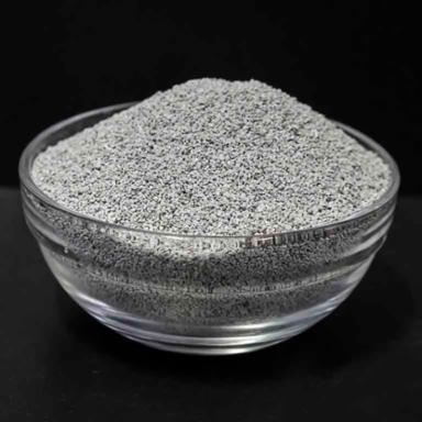 Glass bowl filled with gray clay powder on a black background