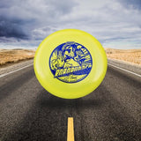 Yellow Disc golf disc with blue design on a desert road under a cloudy sky