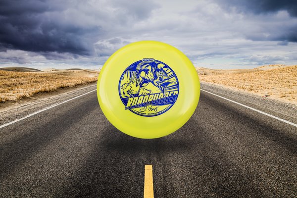 Yellow Disc golf disc with blue design on a desert road under a cloudy sky