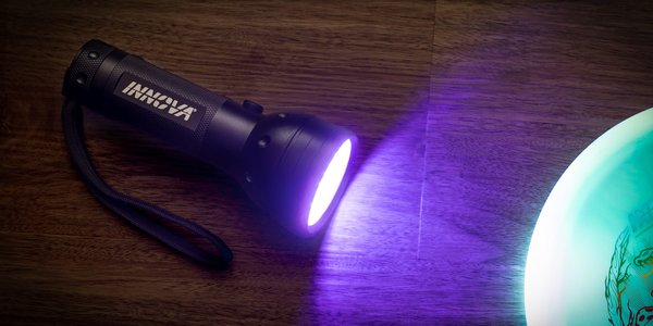 UV flashlight emitting purple light on a wooden surface