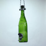 Green glass wine bottle with a metal bird feeder attached on a white background